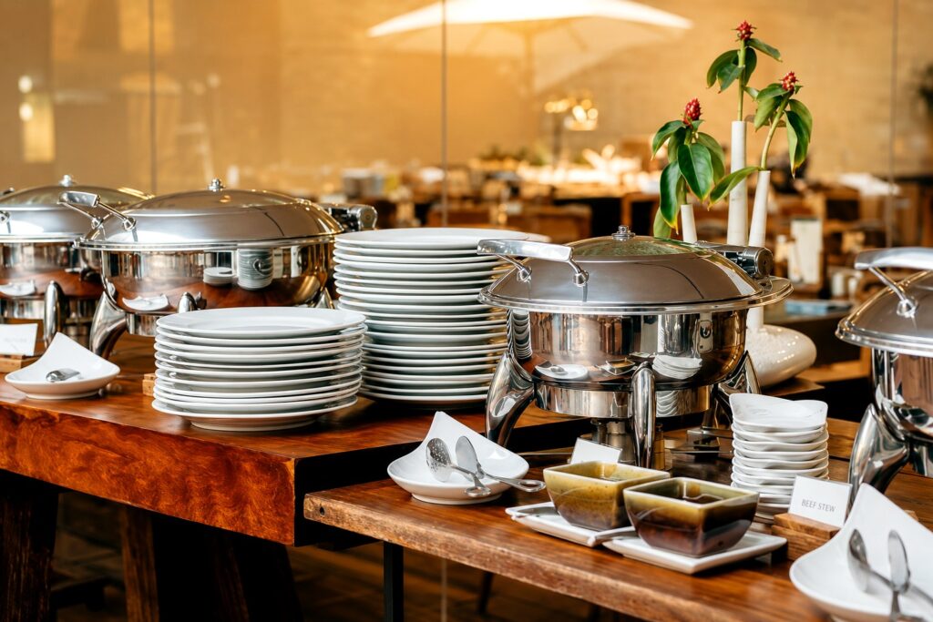 Indoor buffet setup with polished chafing dishes and stacked plates